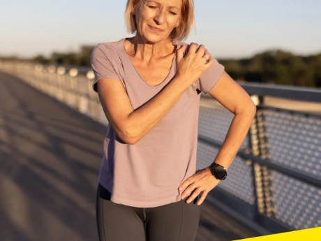 A woman touching her shoulder in discomfort or pain.