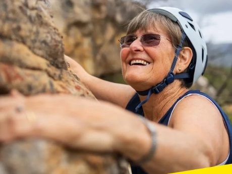 An image of a woman rock climbing while smiling.