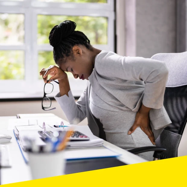 A woman holds her lower back due to discomfort or pain.