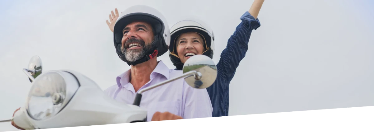 A man and woman smiling while on a moped.