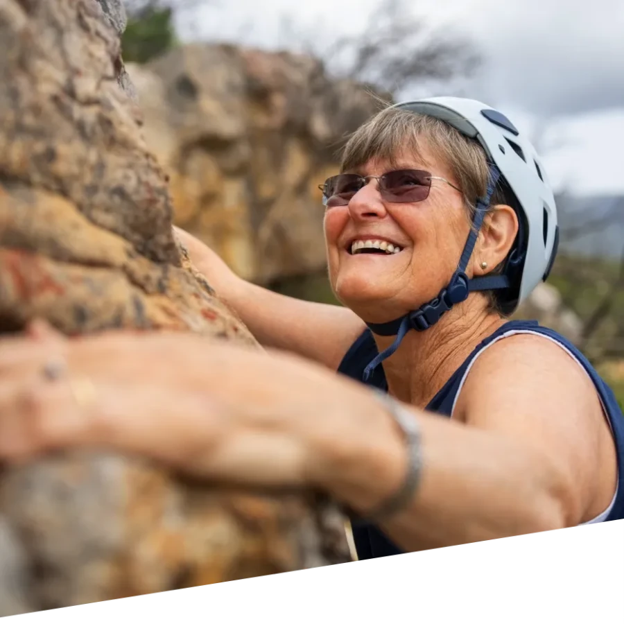 An image of a woman rock climbing while smiling.