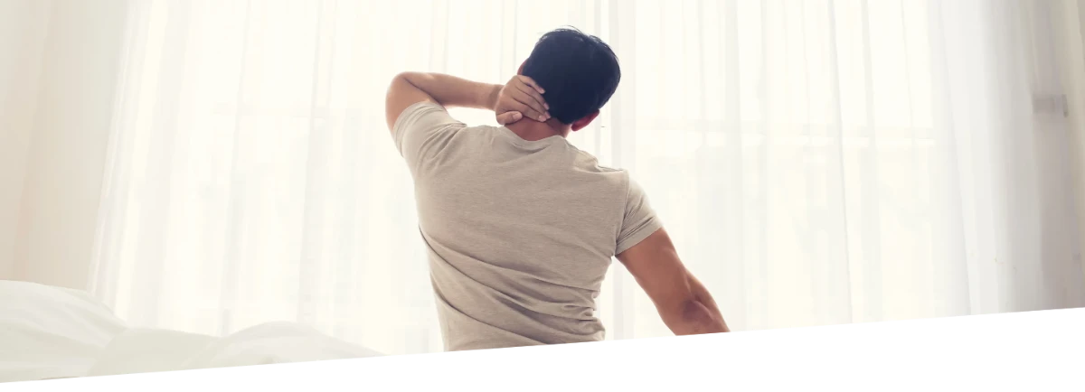 A man holds his neck and seems to be in pain or discomfort.