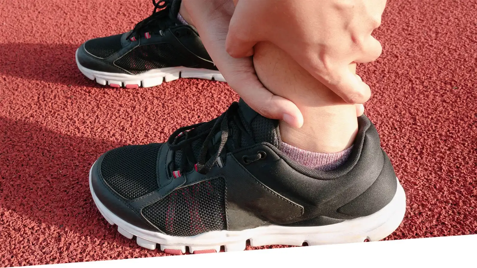 A man grips his ankle as if in pain.