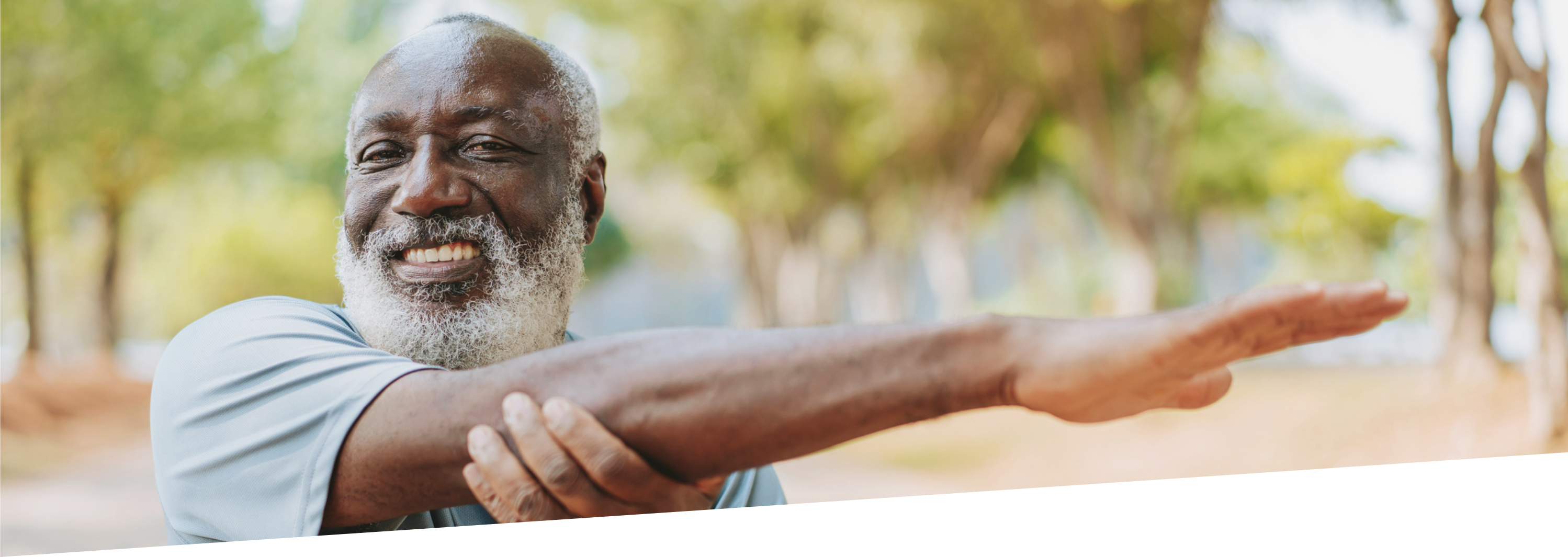 Middle-aged man performs back stretches in a park