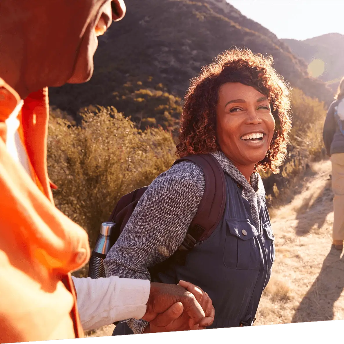 A woman happily stands outside while on a hike.